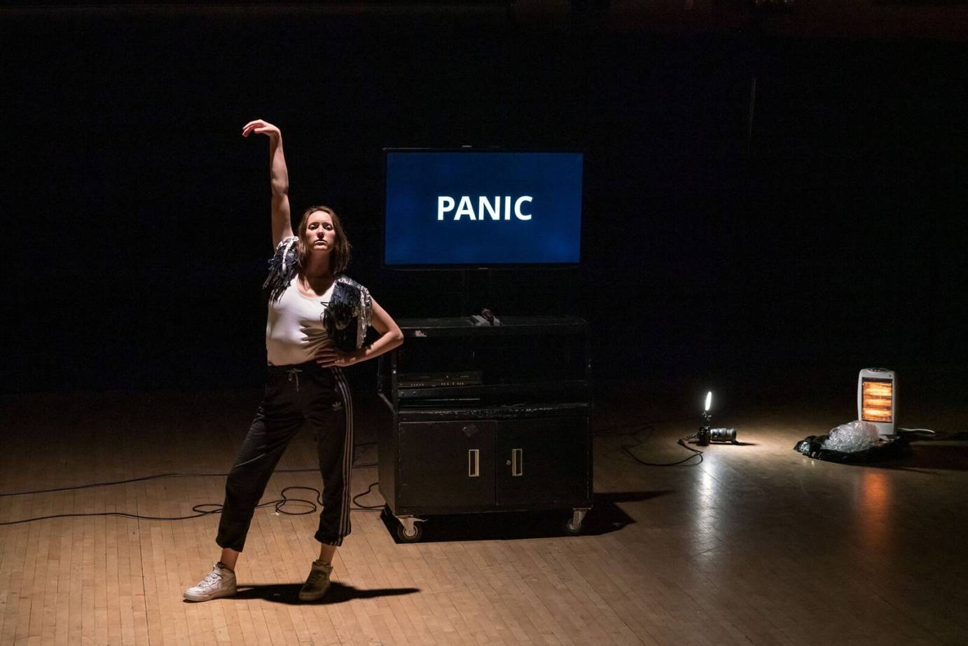 A woman strikes a disco pose in front of a video that says PANIC